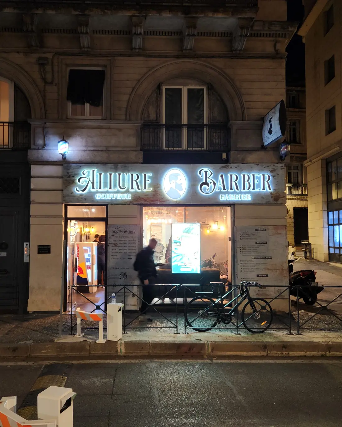 La devanture éclairée d'Allure Barber à Montpellier, le soir